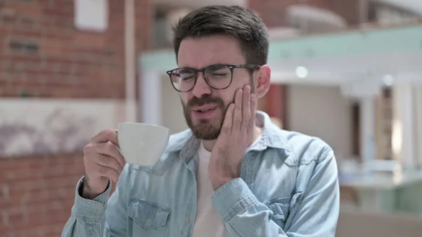 Mladý muž v brýlích s bolestí zubů při pití chladu — Stock fotografie