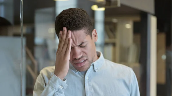 Unavený mladý Afričan s bolestí hlavy v moderní kanceláři — Stock fotografie