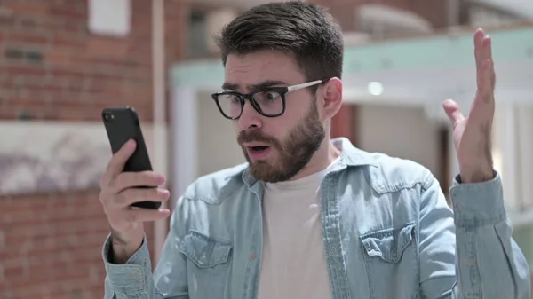 Jonge man in glazen geschokt met behulp van Smartphone — Stockfoto