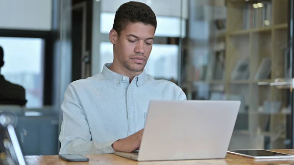 Młody Afrykanin za pomocą laptopa w nowoczesnym biurze — Zdjęcie stockowe