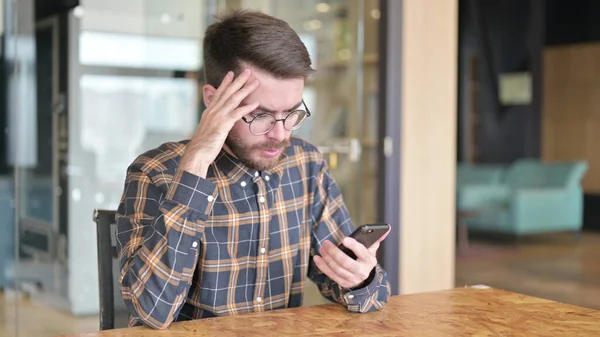 Trauriger Designer mit Smartphone-Verlust im Büro — Stockfoto
