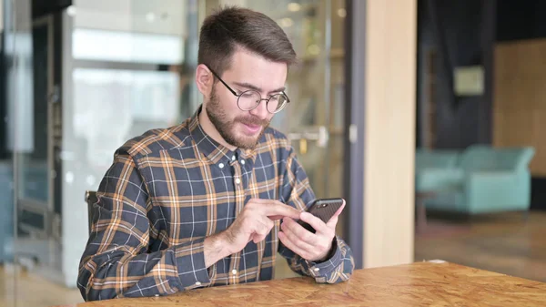 Serious Young Designer using Smartphone in Office — Stock Photo, Image