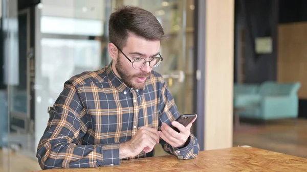 Surpreendido Jovem Designer assistindo resultados no Smartphone — Fotografia de Stock