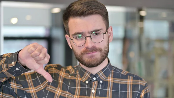 Retrato de un joven diseñador mostrando pulgares hacia abajo —  Fotos de Stock