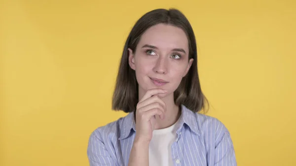 Gondolkodó fiatal nő van új ötlet a sárga háttér — Stock Fotó
