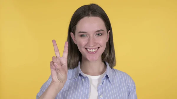 Знак перемоги молодої жінки на жовтому тлі — стокове фото
