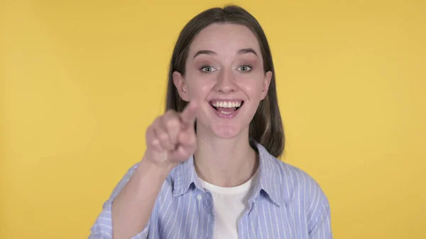 Młoda kobieta zapraszająca klientów obiema rękami na żółtym tle — Zdjęcie stockowe