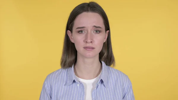 Плаче сумна молода жінка ізольована на жовтому тлі — стокове фото