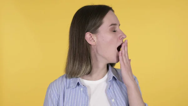 Cansado jovem mulher bocejando em fundo amarelo — Fotografia de Stock