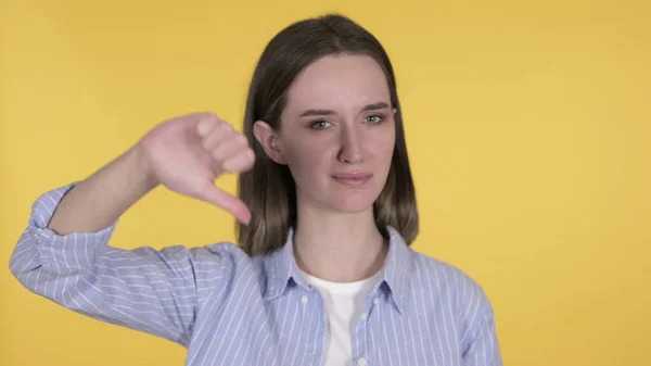 Jovem mulher Gesturing polegares para baixo no fundo amarelo — Fotografia de Stock