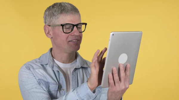 Casual Old Man Browsing Internet on Tablet, Yellow Background