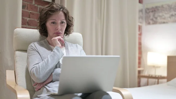 Stara kobieta myśli i pracuje na laptopie w sypialni — Zdjęcie stockowe