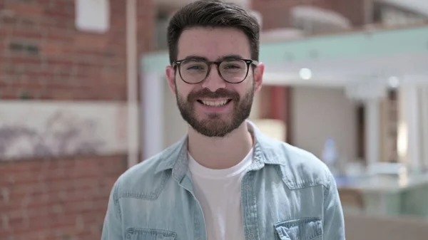 Usmívající se mladý muž v brýlích při pohledu do kamery — Stock fotografie