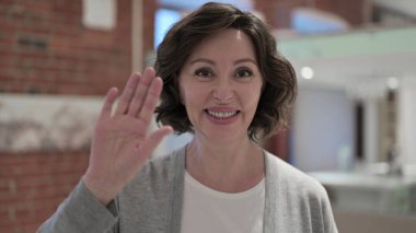 Yaşlı kadının portresi görüntülü konuşma yapıyor, el sallıyor.