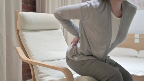 Moe oude vrouw met rugpijn op de bank — Stockfoto