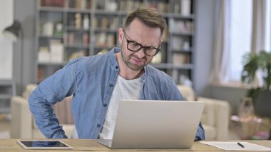 Yorgun genç adam çatı katında sırt ağrısı çekiyor.