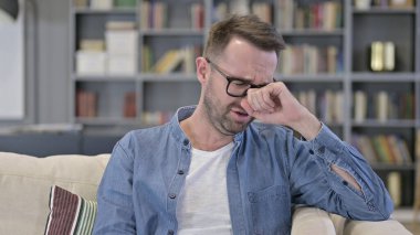 Koltukta oturan ve ağlayan üzgün genç adamın portresi.