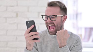 Akıllı telefonda Başarı Kutlaması Yaratıcı Genç Adam