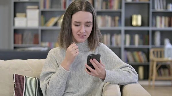 Porträt einer jungen Frau, die auf Verlust mit dem Smartphone reagiert — Stockfoto
