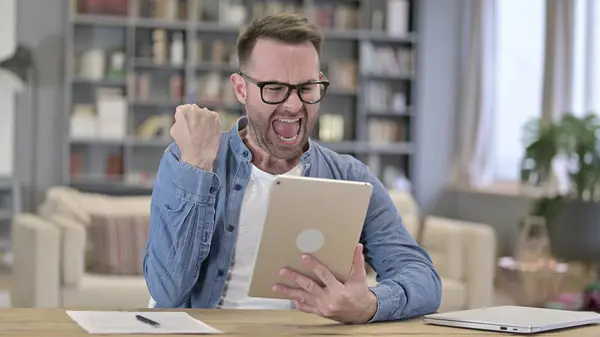 Emocionado joven diseñador celebrando el éxito en la tableta en Loft Office — Foto de Stock