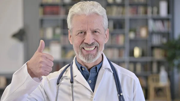 Portret starszego lekarza pokazujący kciuki w górę — Zdjęcie stockowe