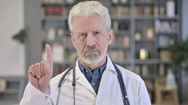 Retrato do velho médico sênior dizendo não com sinal de dedo — Fotografia de Stock