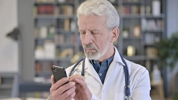 Portret profesjonalnego starszego lekarza korzystającego ze smartfona — Zdjęcie stockowe