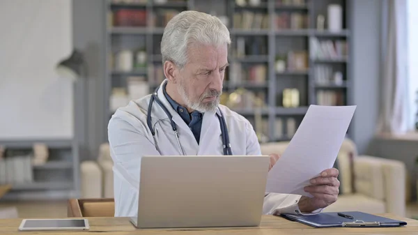 Senior oude arts die medische documenten leest in de kliniek — Stockfoto
