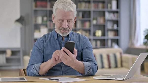 Vieil homme âgé ciblé utilisant un téléphone intelligent dans un bureau moderne — Photo