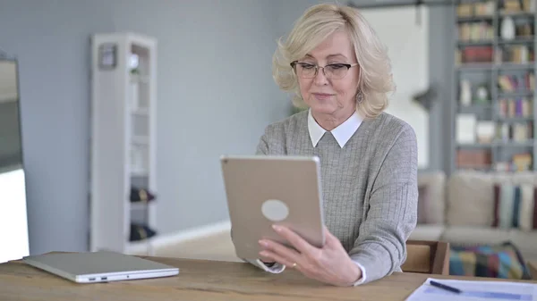 Vieille femme en utilisant la tablette dans le bureau moderne — Photo