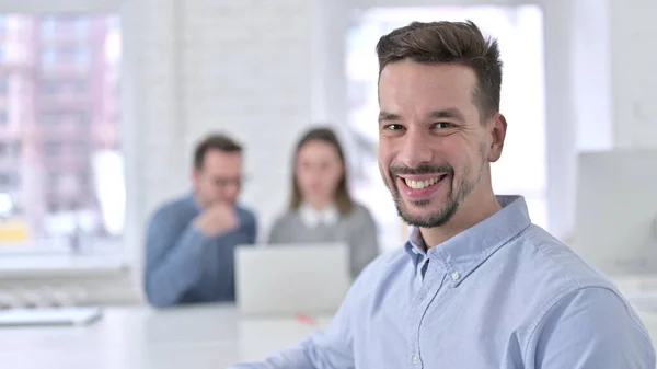 Giovane uomo creativo sorridente alla fotocamera in ufficio — Foto Stock