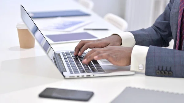 Nahaufnahme eines Afrikaners, der im Büro auf seinem Laptop tippt — Stockfoto