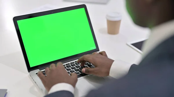 Afrikanischer Geschäftsmann tippt auf Laptop mit grünem Chroma-Schlüsselbildschirm — Stockfoto
