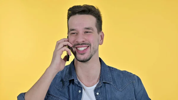 Jovem alegre conversando no smartphone, fundo amarelo — Fotografia de Stock