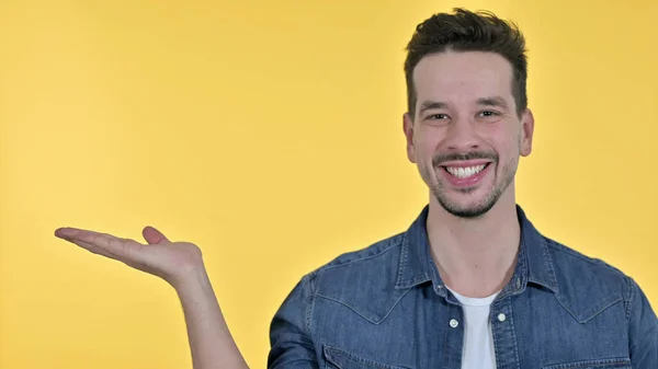 Young Man holding Product on Hand, Yellow Background — 스톡 사진