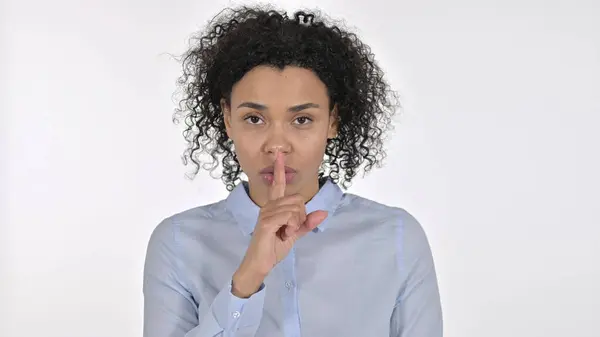 Jovem mulher africana colocando o dedo nos lábios, fundo branco — Fotografia de Stock