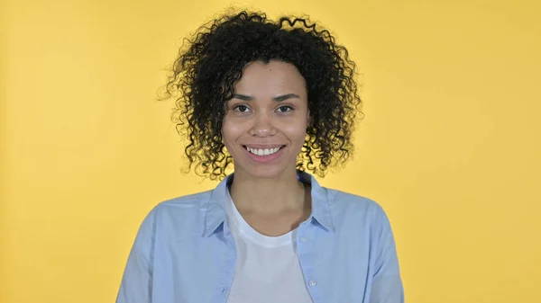 Lässig lächelnde Afrikanerin blickt in die Kamera, gelber Hintergrund — Stockfoto