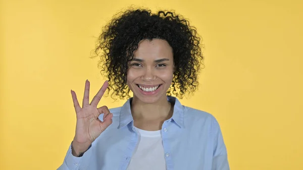 Glada afrikanska kvinna gör OK tecken, gul bakgrund — Stockfoto