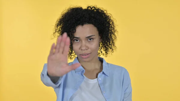 Afrikanerin zeigt Stoppschild von Hand, gelber Hintergrund — Stockfoto