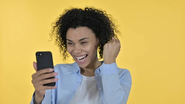 아프리카 여자가 스마트폰 , 노란 배경에서의 성공 을축하 하다 — 스톡 사진