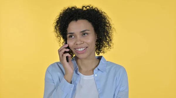 Fröhliche Afrikanerin im Gespräch auf Smartphone, gelbem Hintergrund — Stockfoto