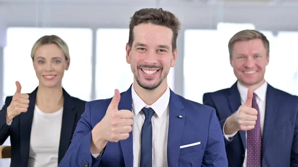 Портрет веселой бизнес-команды, показывающей большие пальцы в офисе — стоковое фото