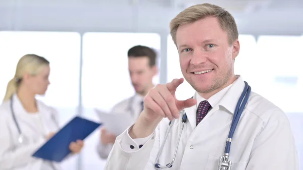 Male Doctor Pointing toward Camera