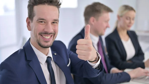 Portret van een vrolijke zakenman met duimen op kantoor — Stockfoto