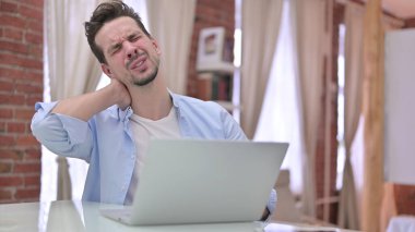 Yorgun genç adam evde boyun ağrısı çekiyor.