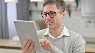 Oturma odasında tablet kullanan neşeli genç adam.