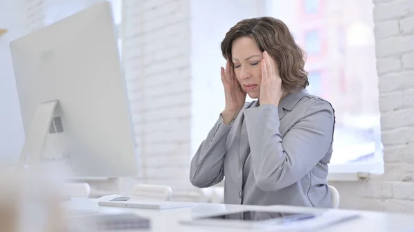 Müde kreative alte Frau mit Kopfschmerzen im Büro — Stockfoto