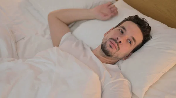 Unavený mladý muž se snaží spát v posteli — Stock fotografie