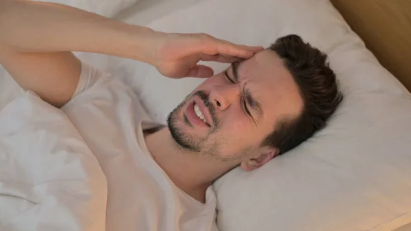 Retrato de un joven con dolor de cabeza en la cama —  Fotos de Stock