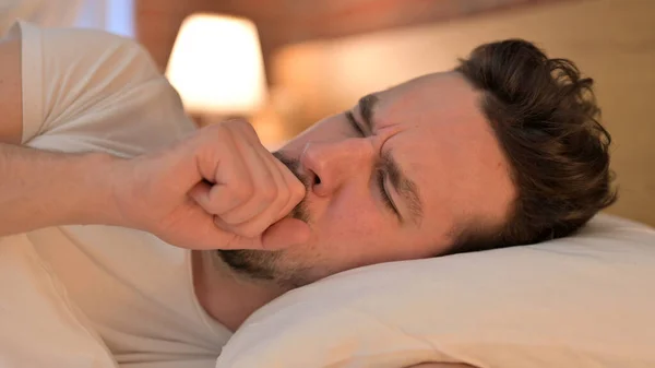 Sjuk ung man som har hosta i sängen — Stockfoto